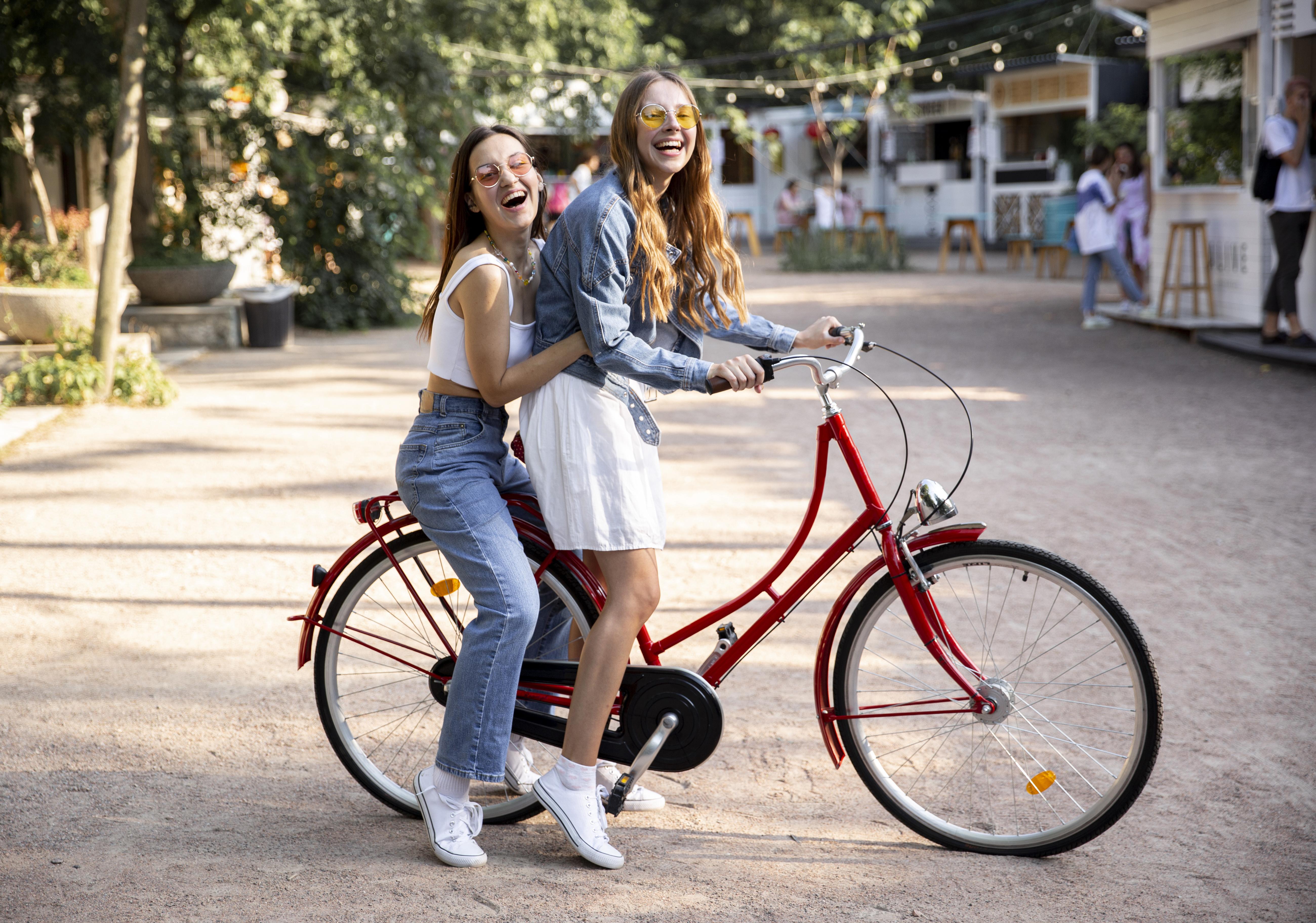 Side view girlfriends riding bike together